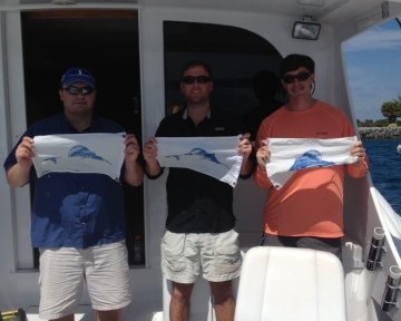 Men holding blue marlin flag on boat